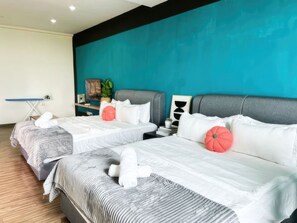 A hotel room with two beds, a blue accent wall, and a wooden floor. - Zetapark Condominium by Emily in Town (Kuala Lumpur)
