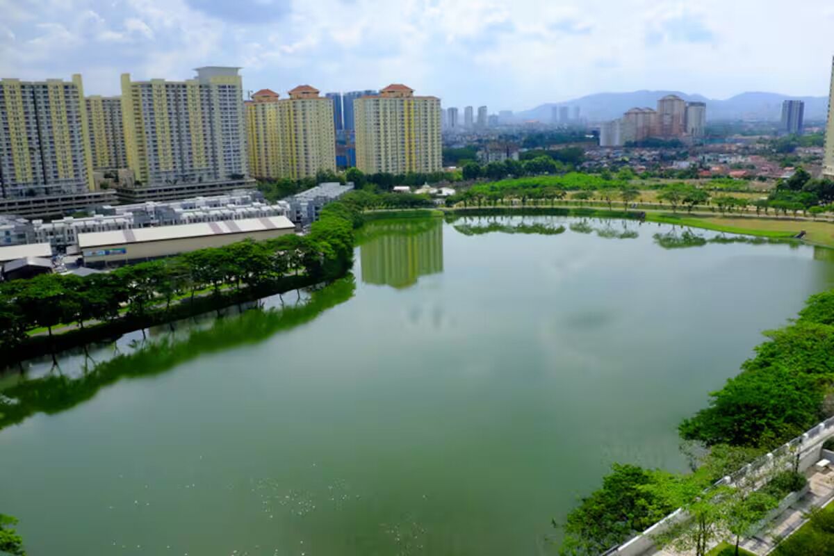 A large body of water surrounded by greenery and high-rise buildings.