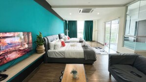A modern hotel room with a large bed, a sofa, a coffee table, and a TV on the wall. - Zetapark Condominium by Emily in Town (Kuala Lumpur)