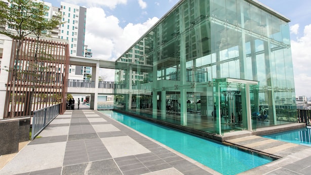 A modern building with a glass facade, a swimming pool, and a tiled walkway. - Zetapark Condominium by Emily in Town (Kuala Lumpur)