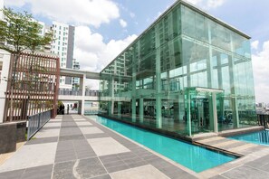 Een modern gebouw met een glazen gevel, een zwembad en een betegelde looppad.