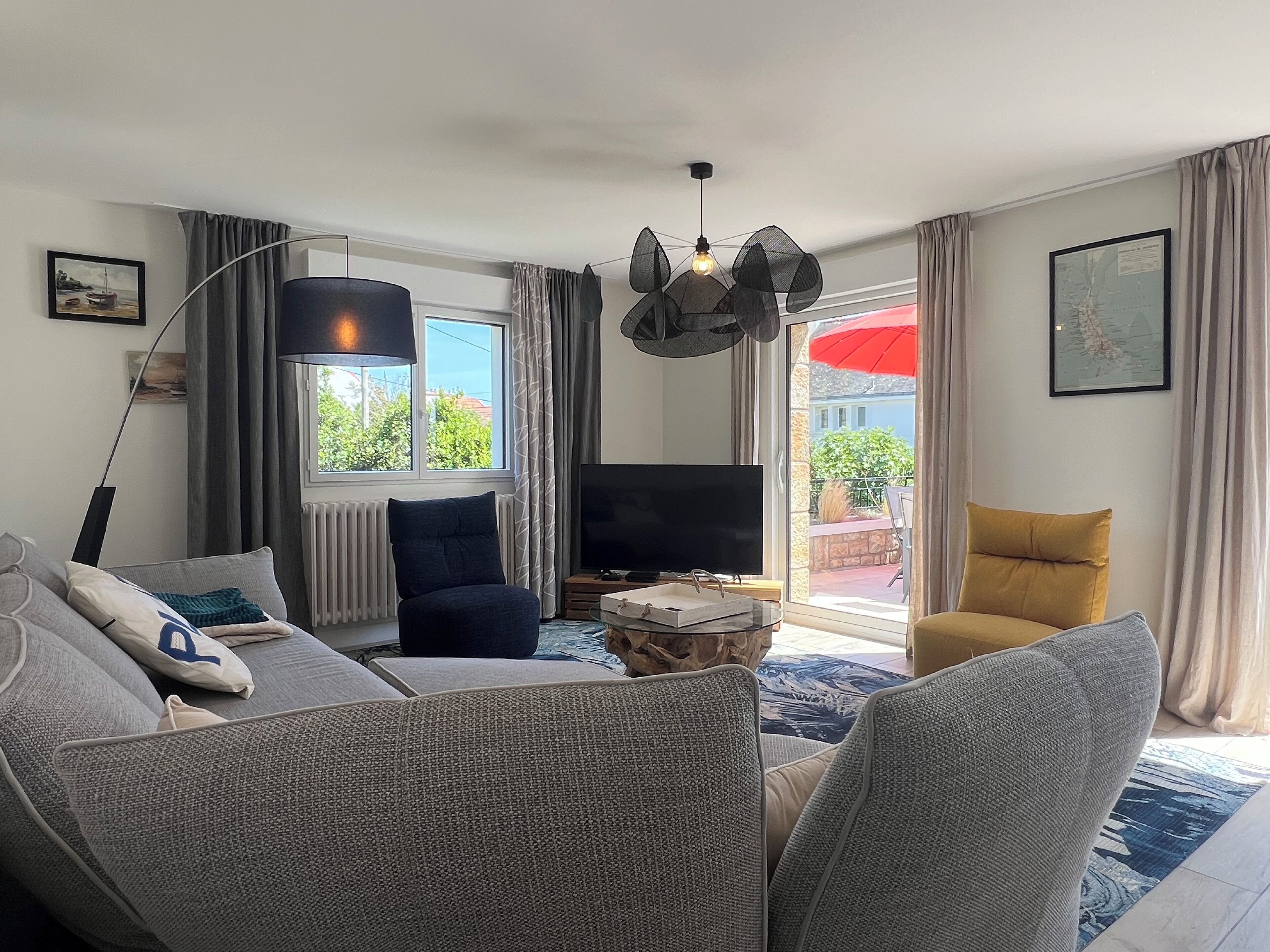 A living room with a sofa, a television, a lamp, and a view of the outdoors.