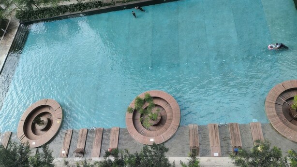 Una amplia piscina al aire libre con un área de cubierta de madera circular y sillones de descanso.
