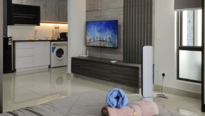 Una sala de estar moderna con un televisor de pantalla plana, un sofá y una lavadora al fondo.