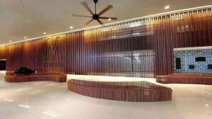 A modern lobby with a wooden slatted wall, a ceiling fan, and a reception desk.