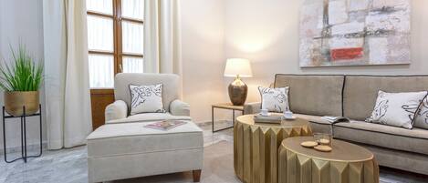A modern living room with a sofa, armchair, coffee table, lamp, and abstract art on the wall.
