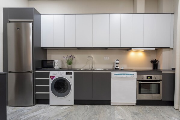 A modern kitchen with a built-in washing machine, dishwasher, oven, and a microwave.