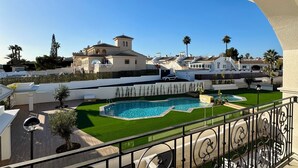 A residential area with a swimming pool, a well-maintained lawn, and a view of neighboring houses.