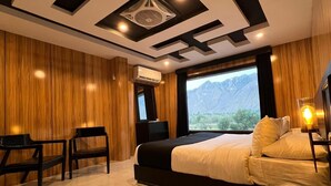 Una habitación de hotel moderna con una cama grande, un escritorio y vistas a las montañas.