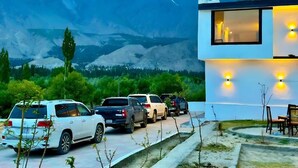 Un edificio moderno con zona de estacionamiento y vistas a la montaña.