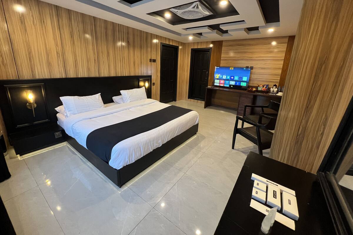 Una camera d'hotel moderna con un letto grande, una scrivania e una televisione.