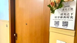 Una puerta de madera con un letrero encima que muestra un código QR y texto en un idioma extranjero.