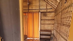 Une pièce avec un sol carrelé, un mur en bois orné d’un motif tissé et un rideau.