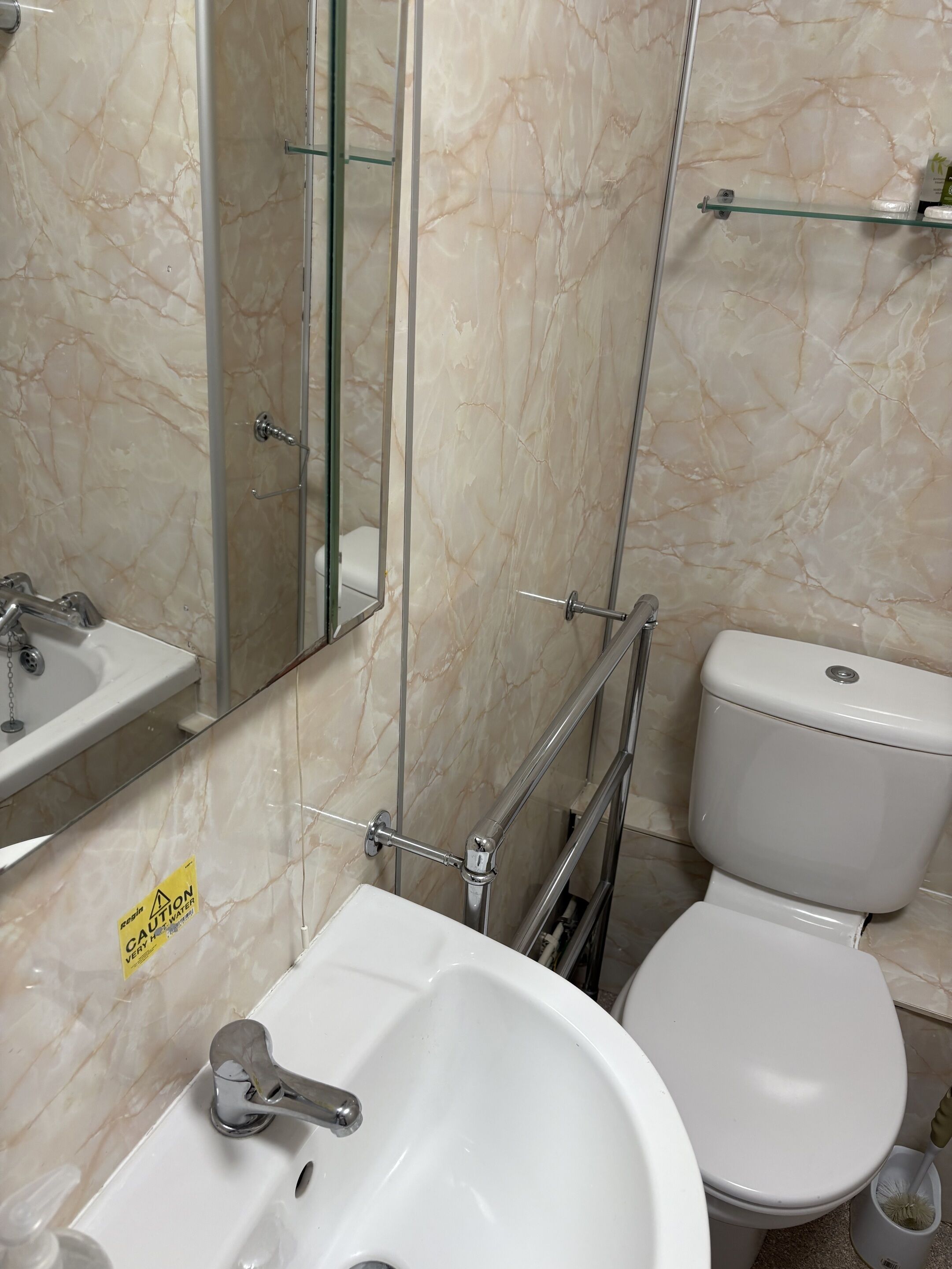 A bathroom with a white sink, mirror, and toilet.