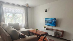 Ein modernes Wohnzimmer mit einer Couch, einem Couchtisch und einem Fernseher.