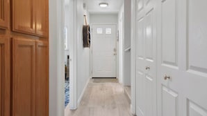A hallway with white doors, wooden cabinets, and a blue carpet.