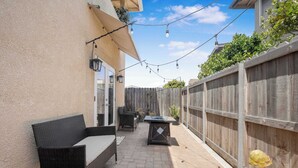 A patio with outdoor furniture, a table, and string lights.