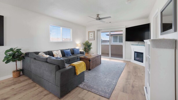A modern living room with a grey sectional sofa, a wooden coffee table, a large flat-screen TV, and a fireplace.