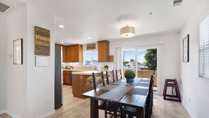 A modern kitchen with wooden cabinets, a central island, and a dining area with a wooden table and chairs.