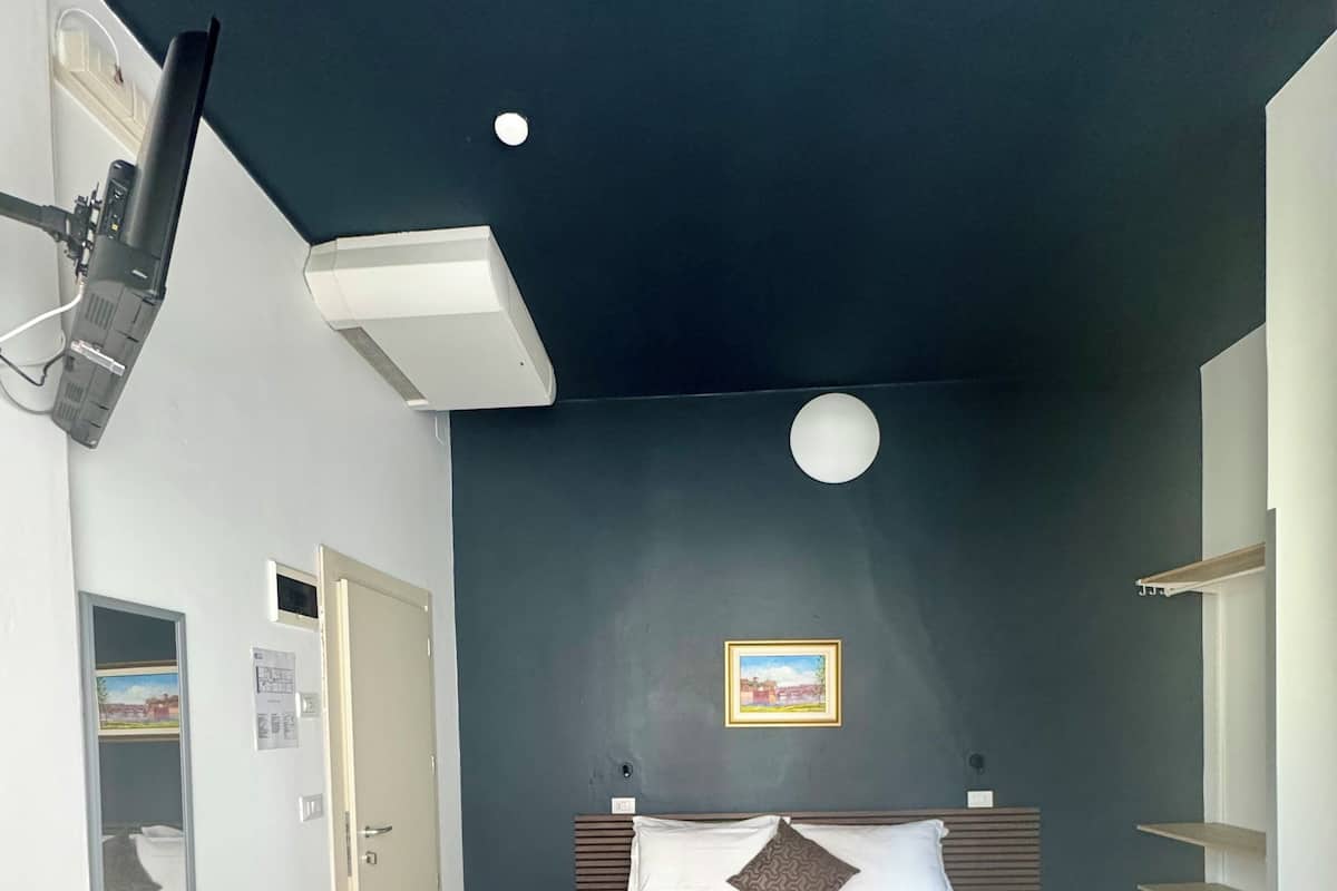 Un dormitorio con cama, mesitas de noche, escritorio y silla.