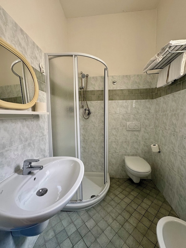 A bathroom with a shower, toilet, sink, and a mirror. - HOTEL DINKLI (Rimini)