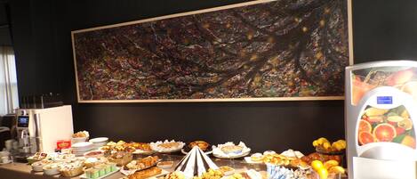 A buffet with various food items and a large abstract painting on the wall.