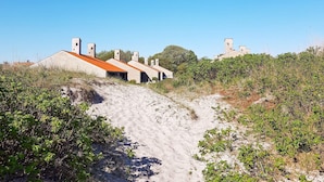 A series of buildings with a sloped roof, situated on a sandy terrain with sparse vegetation. - 6 Person Holiday Park Home in Saeby (Sæby)
