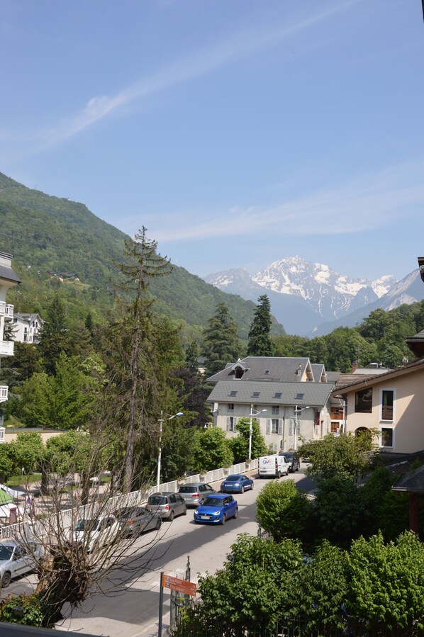 A residential street with houses, parked cars, and a mountain backdrop.