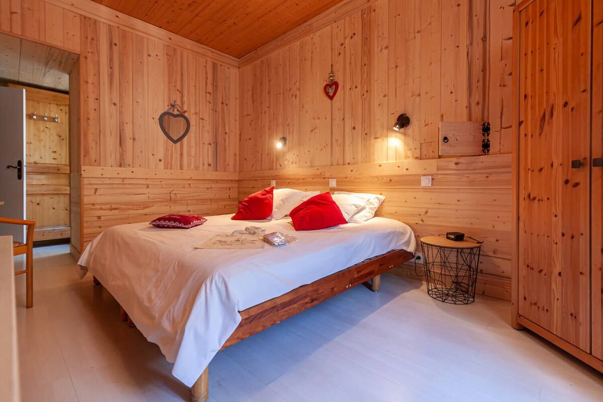 Une pièce en bois avec un lit, une petite table ronde et un décor en forme de cœur sur le mur.