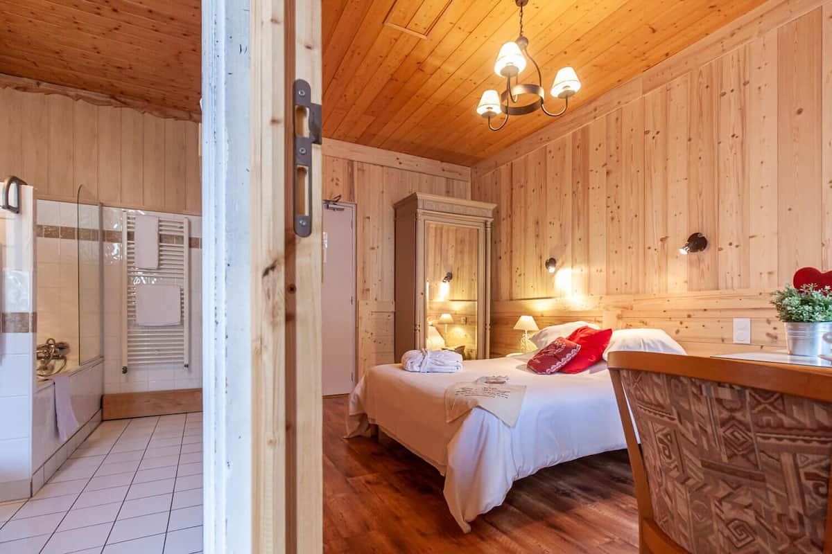 Une chambre dans une cabane en bois, avec un lit, des lampes de chevet et une tête de lit en bois.