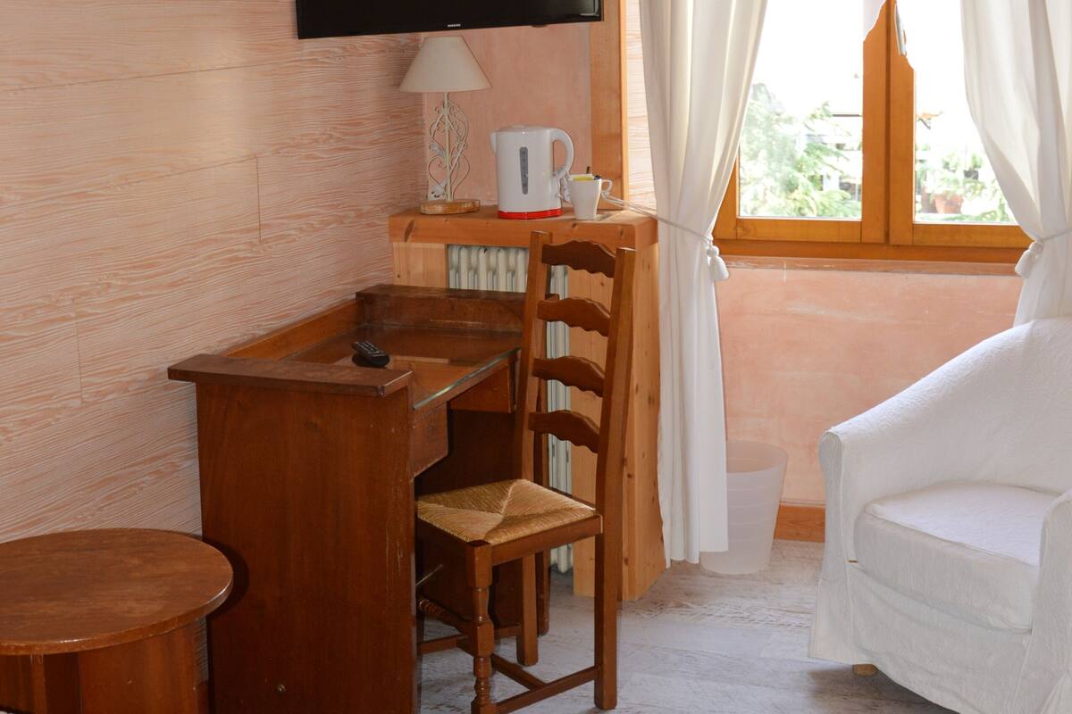 Une pièce confortable avec un bureau en bois, une chaise, un lit et un téléviseur fixé au mur.