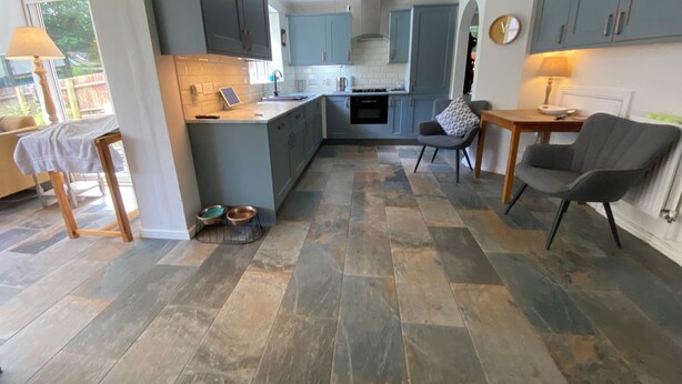 A modern kitchen with blue cabinets, a central island, and a dining area with a table and chairs. - Charming Friendly bed & breakfast in serene north Cardiff with WiFi (Thornhill)