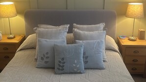 A neatly made bed with a grey headboard, flanked by two bedside tables with lamps and a small clock. - Charming Friendly bed & breakfast in serene north Cardiff with WiFi (Thornhill)