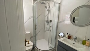 A bathroom with a glass-enclosed shower, a toilet, a sink with toiletries, and a mirror. - Charming Friendly bed & breakfast in serene north Cardiff with WiFi (Thornhill)