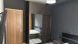 Ein Schlafzimmer mit Bett, Kleiderschrank, Spiegel und Nachttisch.