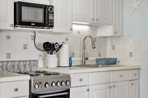 Fully equipped coastal kitchen with crisp white cabinetry and charming seashell-patterned tiles. Everything you need for beachside cooking adventures. - Rare Waterview Resort Condo on Clearwater Beach! (Clearwater)