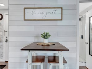 A dining area with a table and benches, a framed sign above, and a potted plant on the table. - Water-view studio, heated pool, walk to beach (Clearwater)