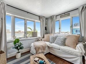 A cozy room with a sofa, a small table, and a view of the beach. - Right on Clearwater Beach! Corner Suite Waterview (Clearwater)