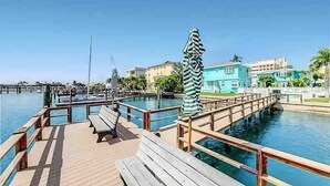 A wooden deck with benches and striped umbrellas overlooking a marina with boats and buildings in the background. - Right on Clearwater Beach! Corner Suite Waterview (Clearwater)
