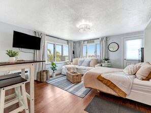 A modern bedroom with a bed, a desk, a TV, and a view of the outdoors. - Right on Clearwater Beach! Corner Suite Waterview (Clearwater)
