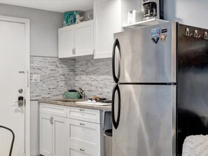 A kitchen with white cabinets, a stainless steel refrigerator, and a tiled backsplash. - Walk 2 minutes to the Beach! Enjoy the Heated Pool (Clearwater)