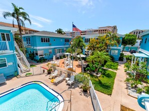 Ein blaues Gebäude mit Pool, Sitzgelegenheiten im Freien und einer Flagge.