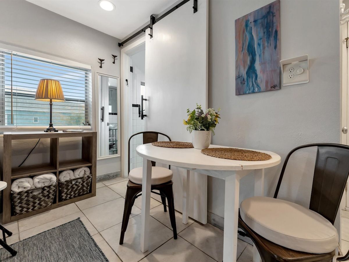 Une cuisine moderne avec une table blanche, deux chaises, une lampe et une plante en pot.