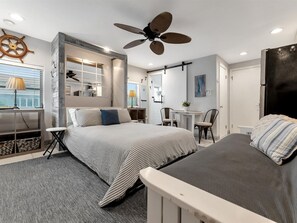 Ein modernes Schlafzimmer mit Bett, Schreibtisch und Deckenventilator.