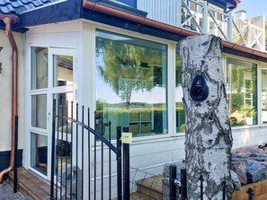 A modern house with large windows, a wooden deck, and a metal fence. - 8 Person Holiday Home in Maribo (Maribo)