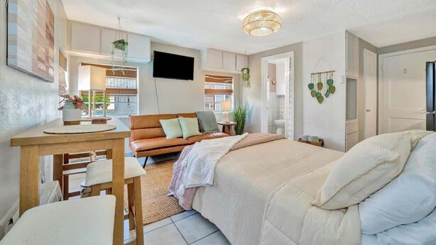 A bedroom with a bed, a desk, a chair, a sofa, and a television. - Resort Condo just 2 Blocks from Clearwater Beach! (Clearwater)