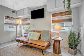A modern living room with a leather sofa, a flat-screen TV, and a small wooden side table.