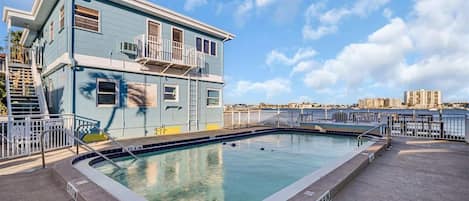 A rooftop pool area with a pool, stairs, and a building with a balcony.