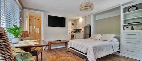 A compact bedroom with a bed, bedside table, and a TV mounted on the wall.