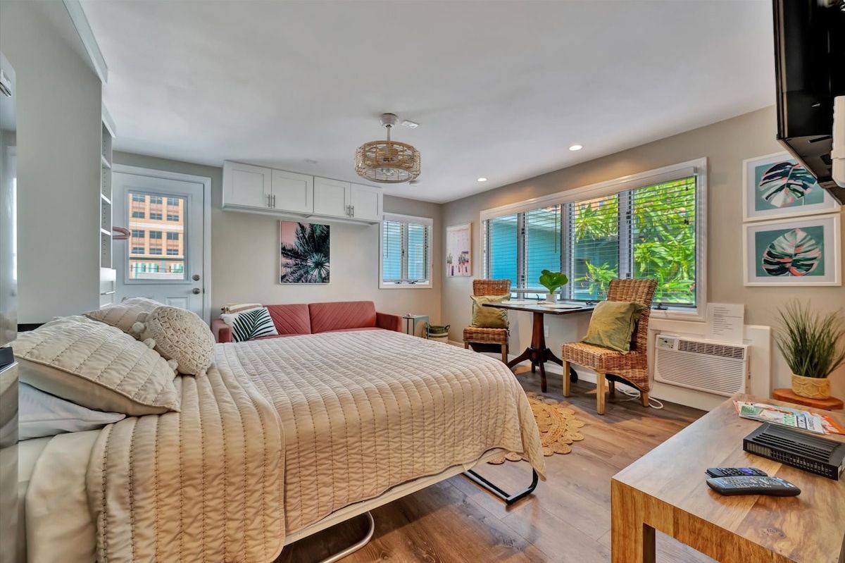 A bedroom with a bed, a desk, a chair, and a window with blinds.